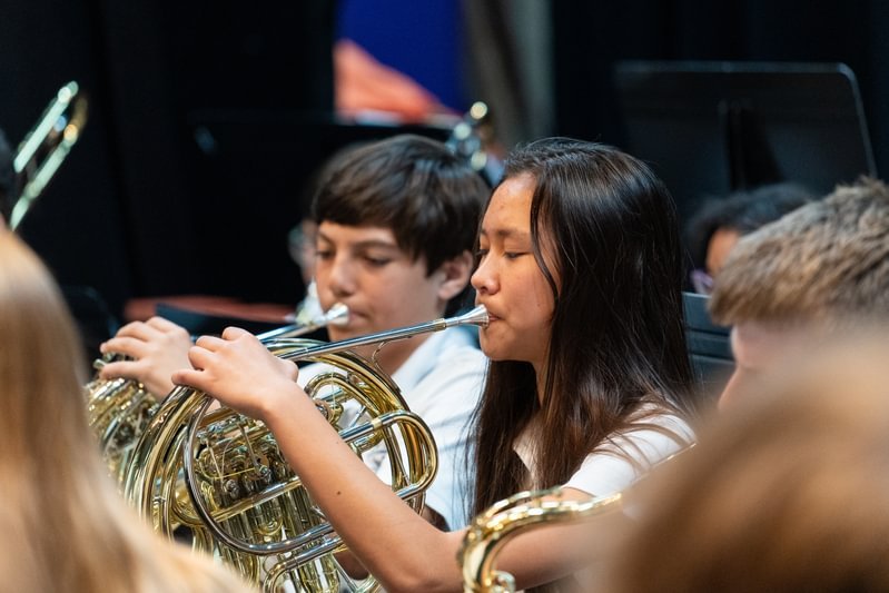 A girl plays the french horn in a band.