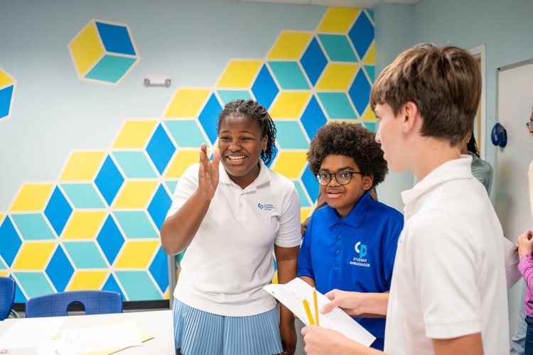 Three students look at each other smiling and laughing.