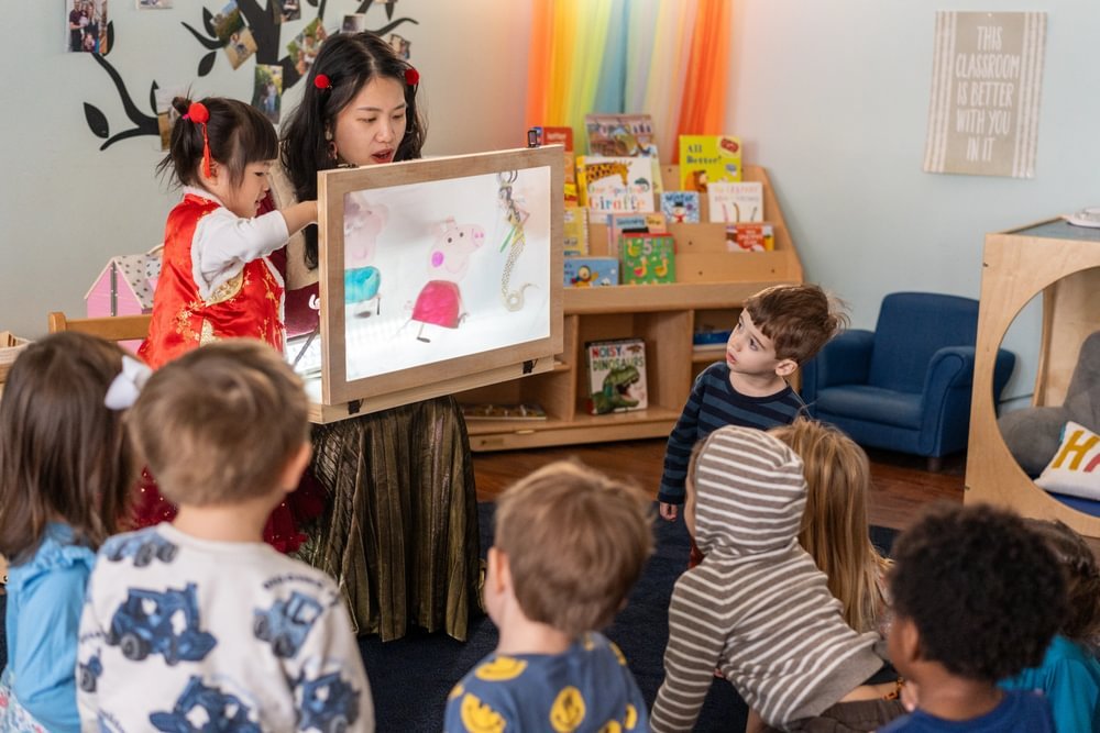 A mother and her daughter present a project to a class of listening students.