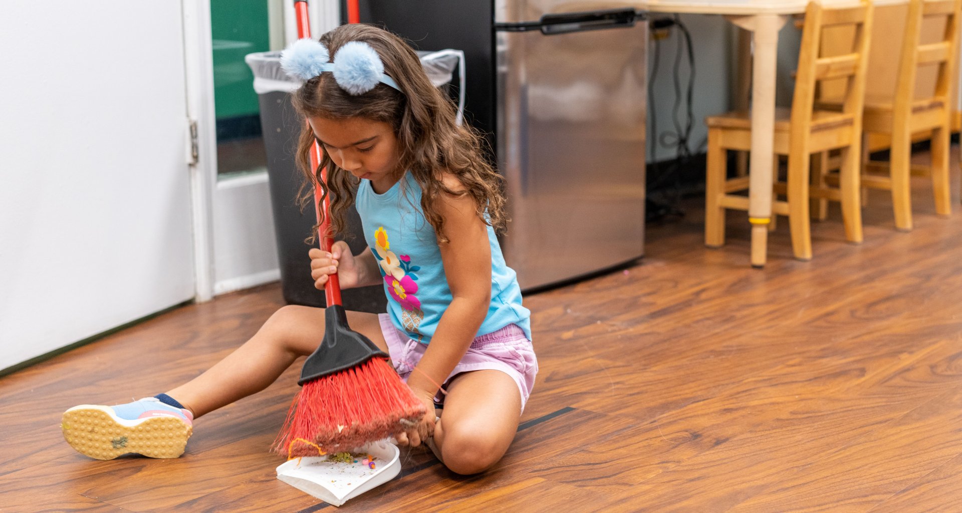 A girl helps clean up a classroom.