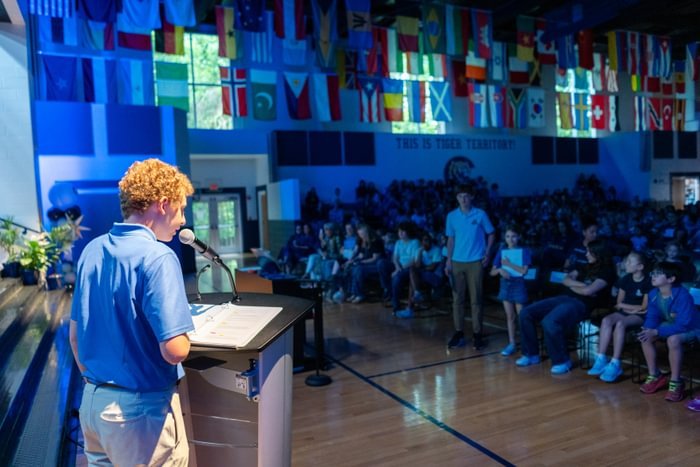 Student speaking at podium in front of crowd of students.