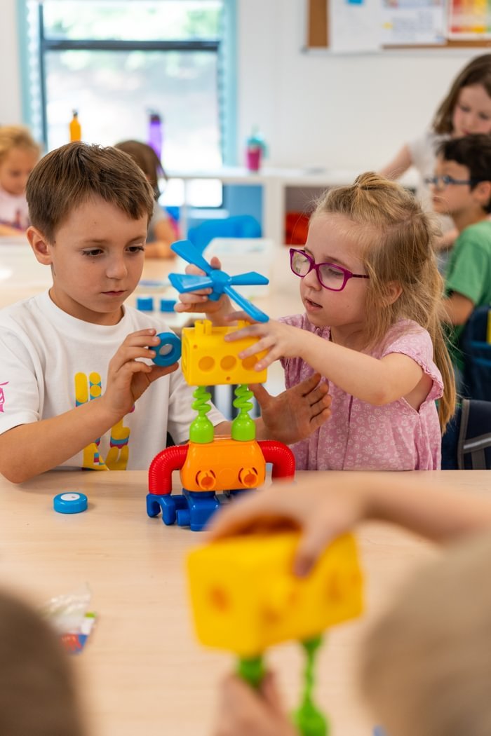 A girl and boy work together to build a colorful project.