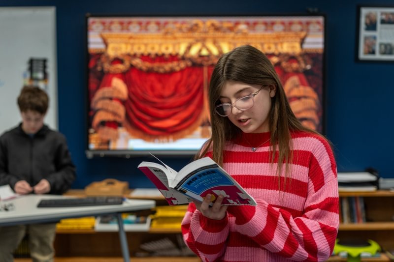 Girl reads a book in a classroom.