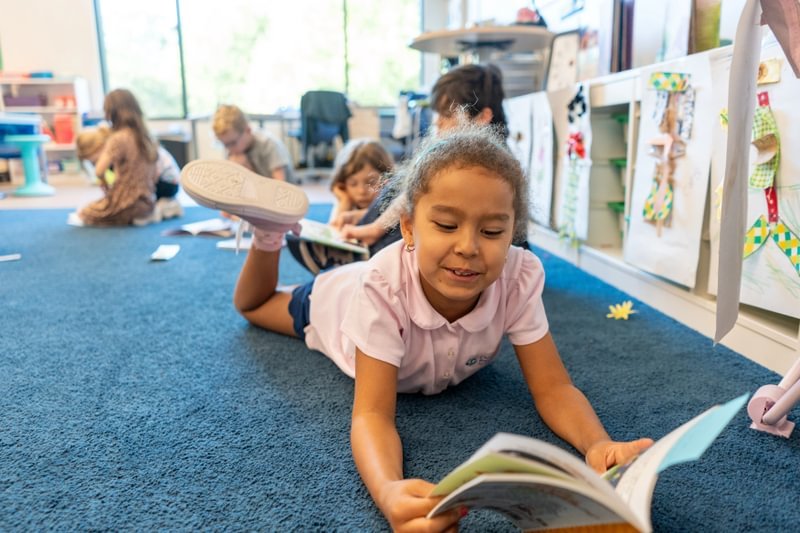 A student sits on the floor and reads a book.