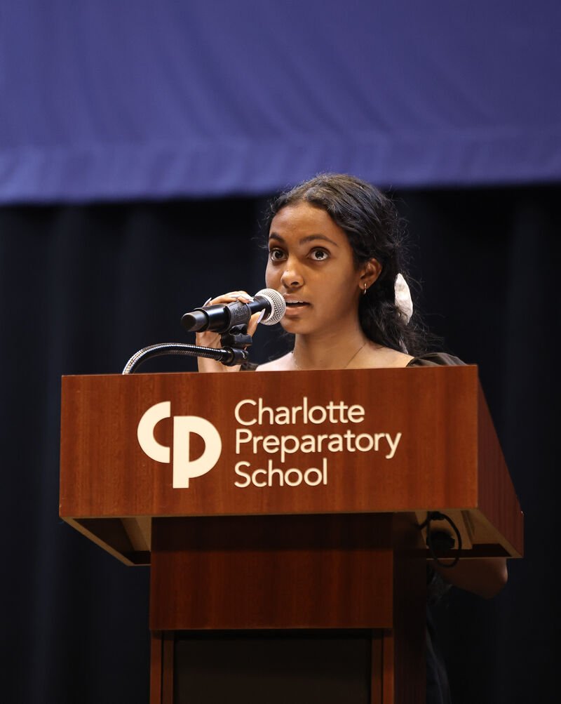 A girl gives a speech at a podium with a microphone.