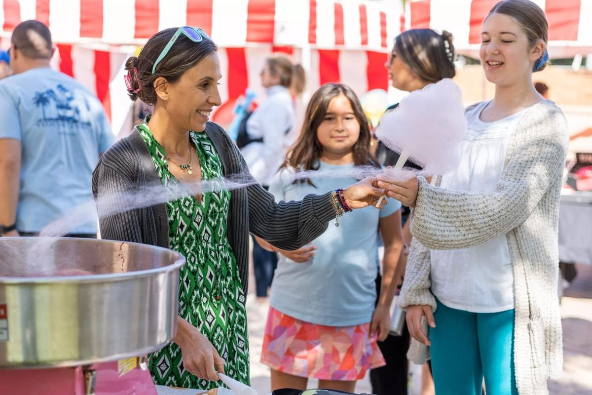 A parent volunteer passes out cotton candy.