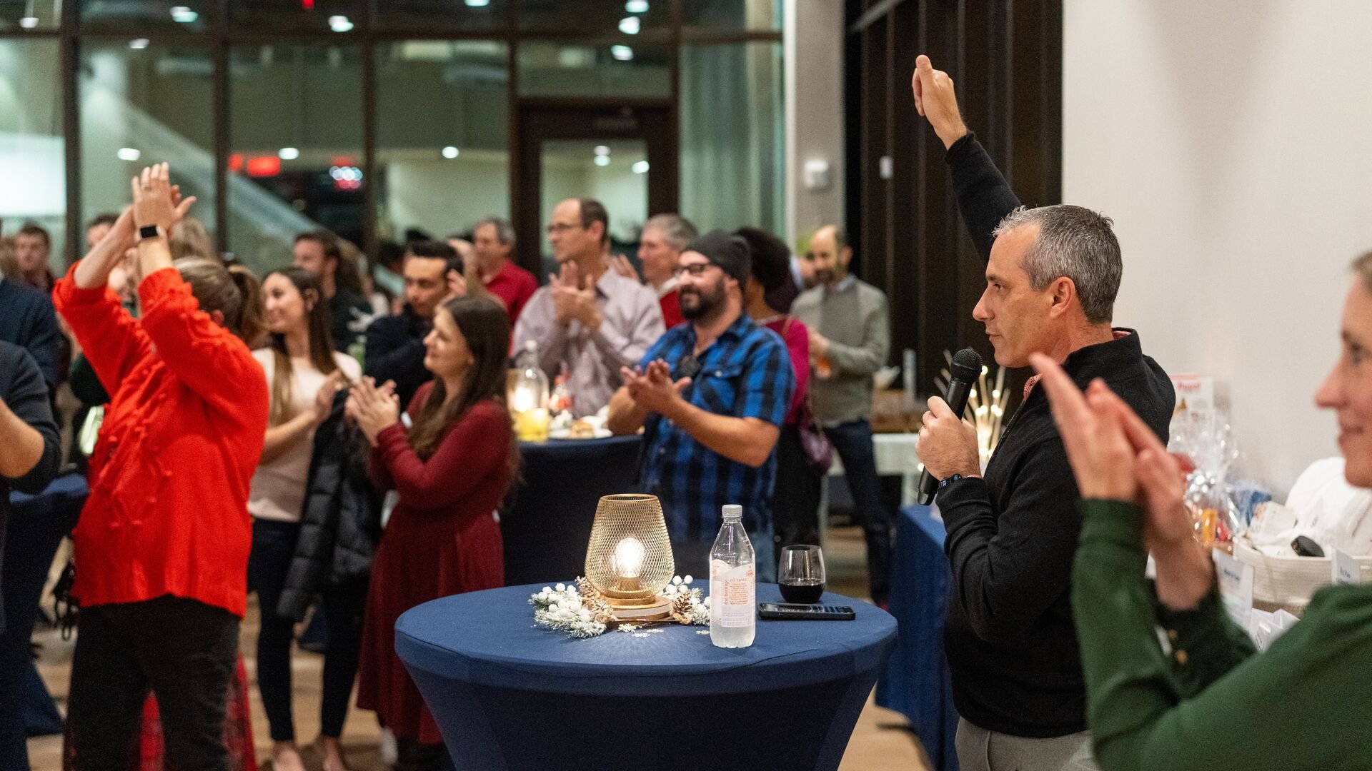 Faculty and staff clap and smile at holiday party
