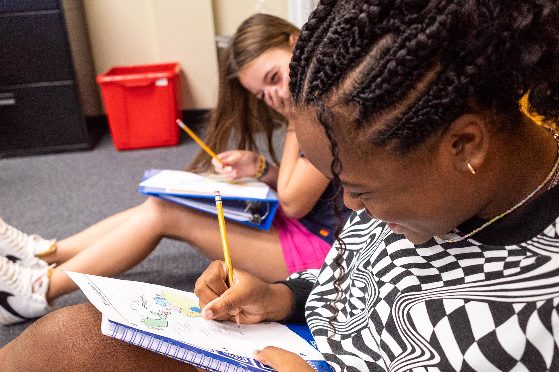 Two students giggle while drawing on a map