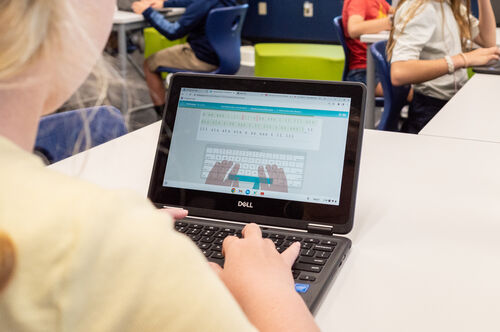 A boy smiles holding a laptop