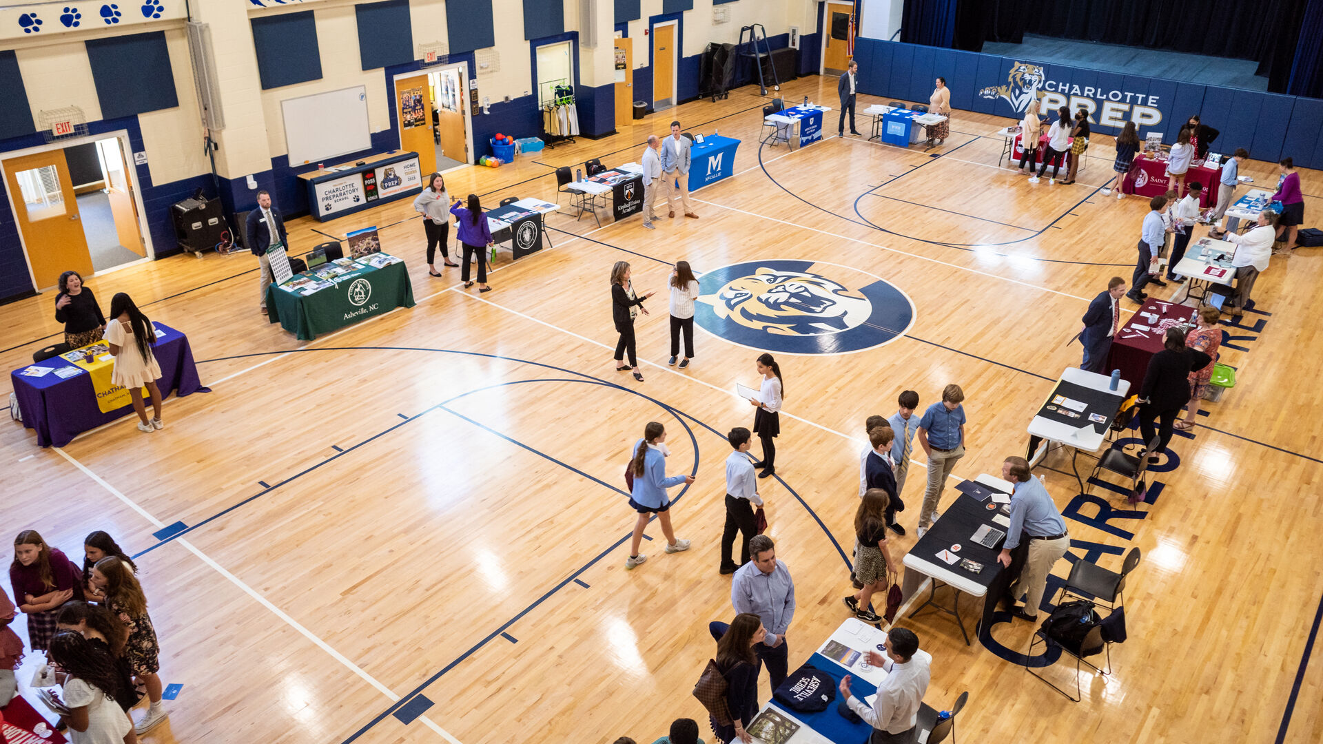 A gymnasium full of tables from different schools