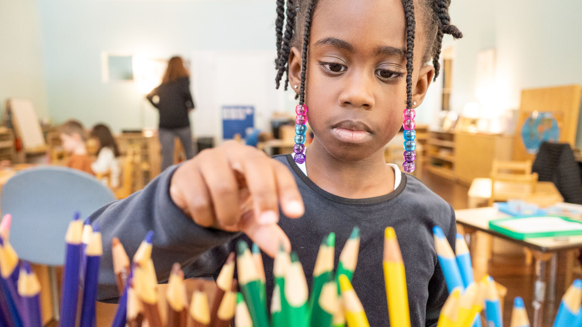 A girl chooses from a box of colored pencils