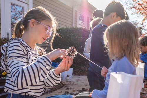 A middle school student in the gardening club helps pre-schoolers with a project.