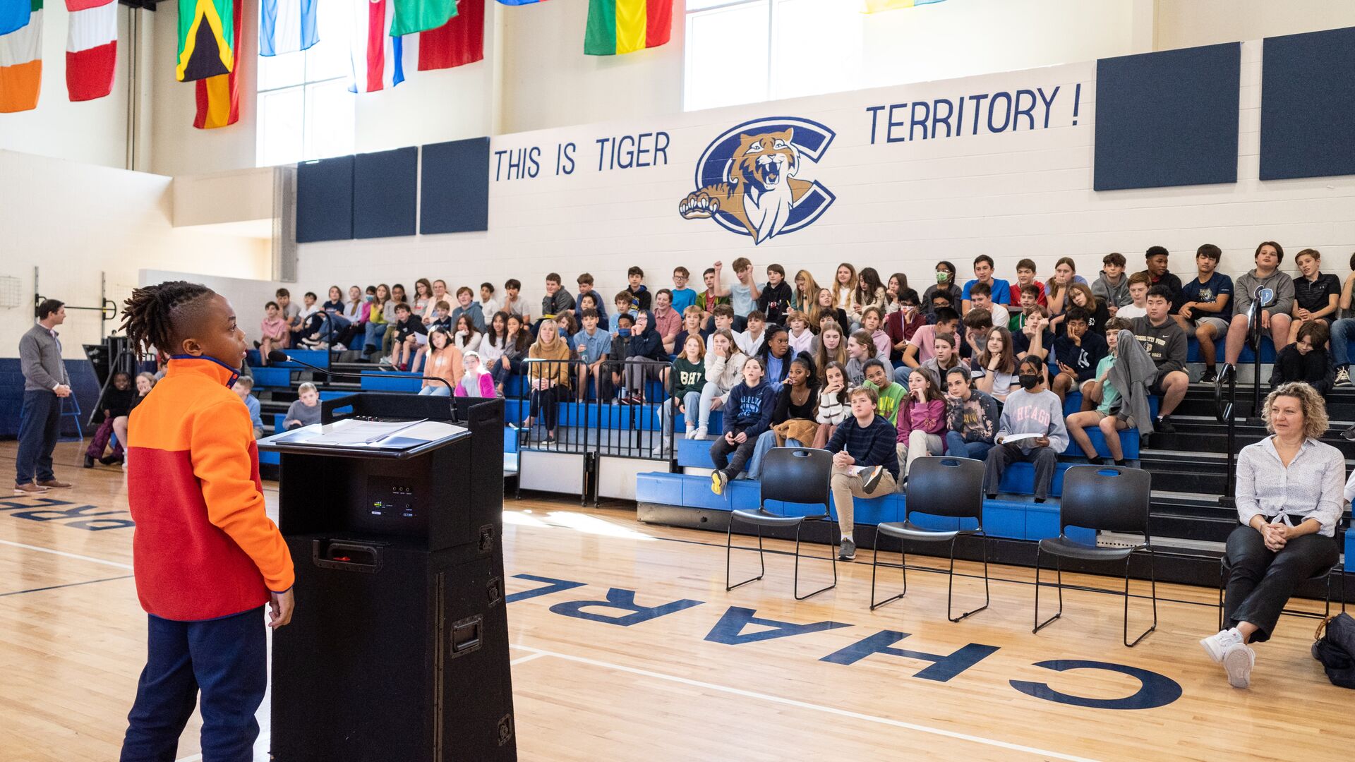 A middle school student speaks in front of the middle school assembly