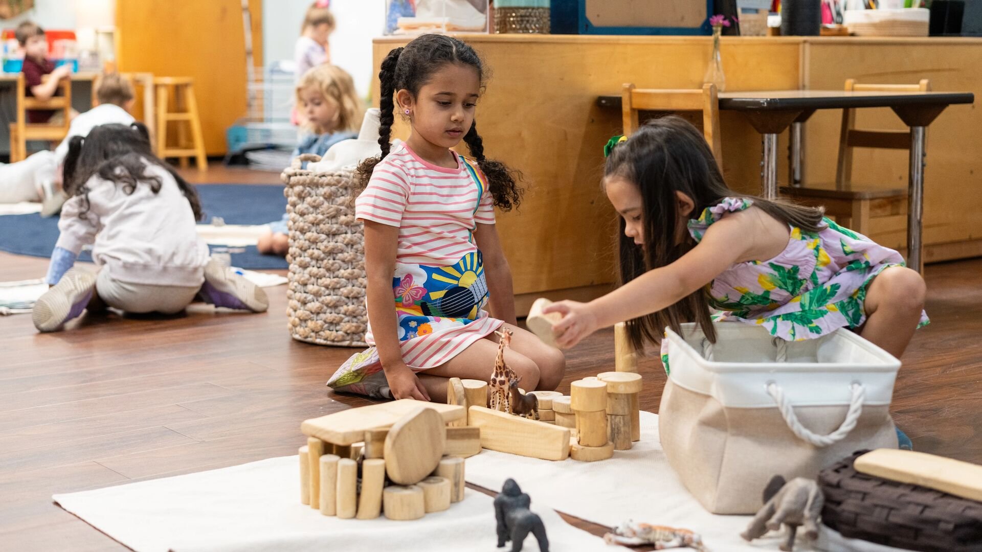 A student waits while another plays with blocks.