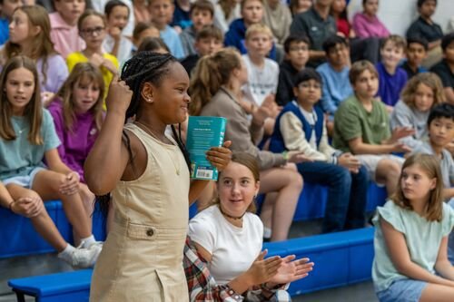 A girl holding a book receives applause
