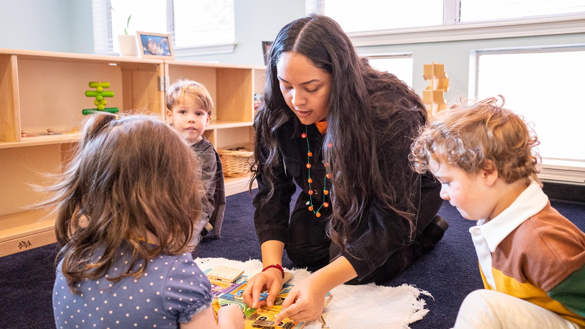 Laura Torres does a puzzle with three small students