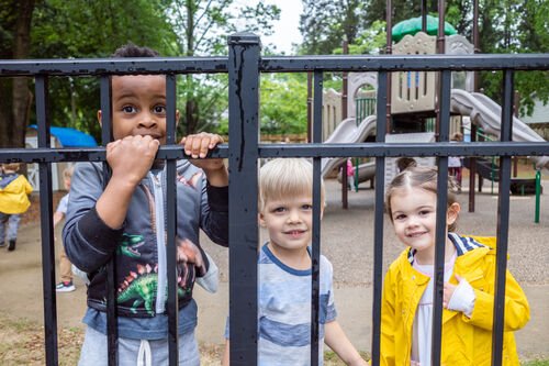 Young students look through the playground fence