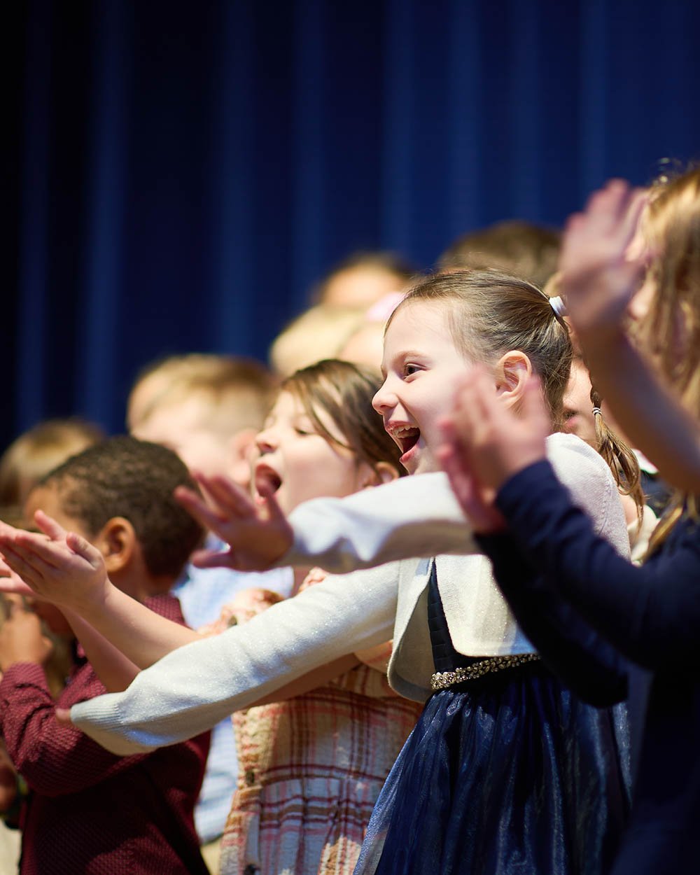 Students smiling and singing on stage.